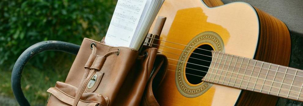 Gitarre und Rucksack auf einer Bank [(c) www.pixabay.com]