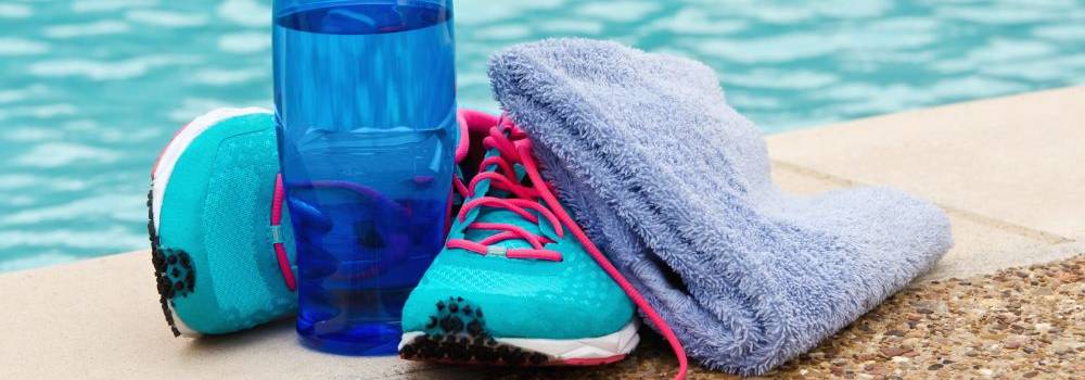 Turnschuhe, Wasserflasche und Handtuch am Schwimmbeckenrand
